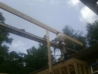 Carpenter setting a ridge beam over a new addition frame — Ice Dam Removal by Roofing Brothers in Oronoco