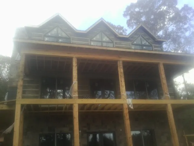 Dormers and porch framing on a large log home under construction — Roof Coating work by our crew in Oronoco