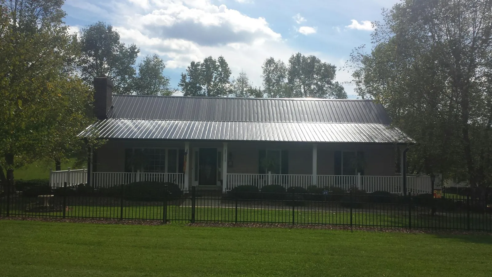 Gray metal roof on a brick ranch with a full width front porch — Gutter Guard Installation work by our crew in Oronoco