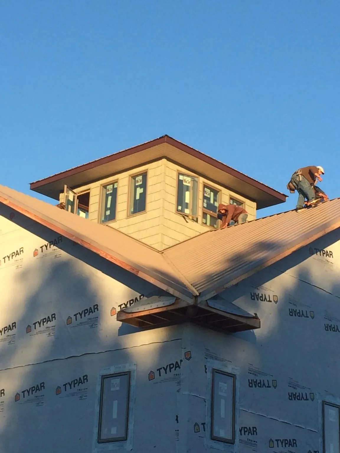 Roofers working around a rooftop cupola on a new metal roof at sunset — Roof Waterproofing in Oronoco by Roofing Brothers